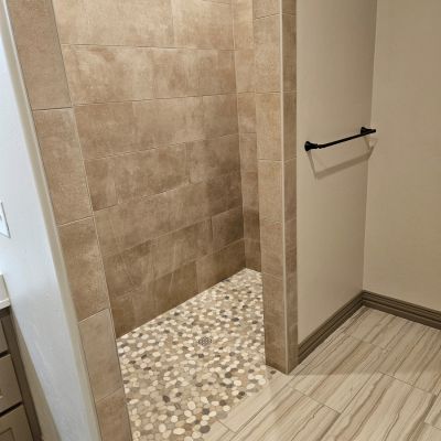 shower with beige tiles and mosaic floor